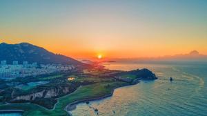 an aerial view of a city and the ocean at sunset at Atour X Hotel Qingdao Shilaoren Beach Exhibition Center Metro Station in Qingdao