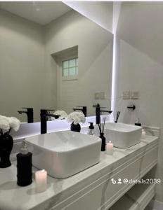 Baño blanco con 2 lavabos y espejo en شاليهات ديتيلز الفندقية, en Al Khafji