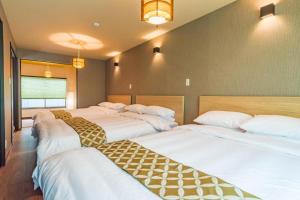 大阪市にあるBijou Suites Kakomiの白いシーツが備わるベッド3台が備わる部屋