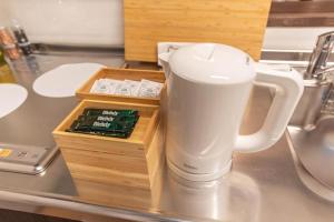 Una taza de café blanca sentada en un mostrador junto a una caja. en Bijou Suites Century en Osaka