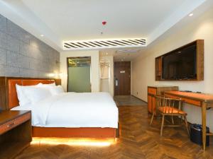 Dormitorio con cama, escritorio y TV en Borrman Hotel Capital Airport Convention & Exhibition Center Auto Market en Tahe