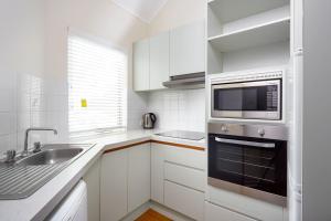 a kitchen with white cabinets and white appliances at Broadwater Resort Como in Perth