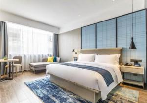 1 dormitorio con 1 cama blanca grande y 1 sofá en Echarm Hotel Quanzhou Liming Vocational University Ling Show World, en Donghai