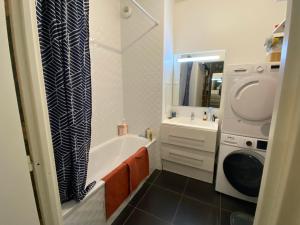 a bathroom with a tub and a sink and a washing machine at Le jardin de Clémentine & Julien in Saint-Ouen