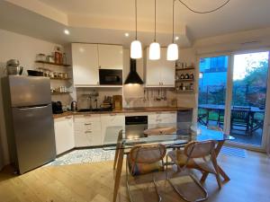 a kitchen with a glass table and a stainless steel refrigerator at Le jardin de Clémentine & Julien in Saint-Ouen