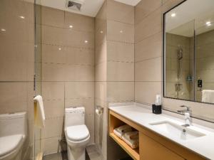 La salle de bains est pourvue de toilettes, d'un lavabo et d'un miroir. dans l'établissement City Comfort Inn Jingzhou Fantawild Shashi Middle School, à Juzhang He