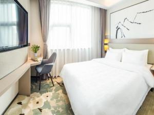 um quarto de hotel com uma cama, uma secretária e uma televisão em GreenTree Eastern Hotel Chongqing Xiejiawan Light Rail Station em Jiulongpo