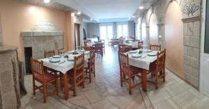 a dining room with tables and chairs and a fireplace at Hospedaje O Canizo in Hio