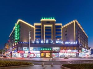 un gran edificio con luces verdes delante de él en Green Tree Inn Zhuhai International Airport Huafa Shangdu en Baigaonongchang
