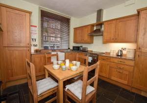 una cocina con armarios de madera y una mesa de madera con sillas. en Fenkle, en Alnwick
