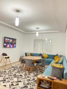 a living room with a blue couch and a table at Appartement standing avec piscine à ImiOuaddar in Agadir