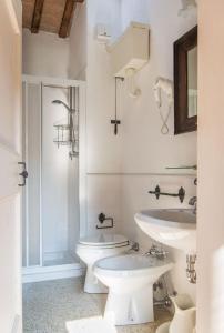 a white bathroom with two sinks and a toilet at Casa Zorzi in Arquà Petrarca