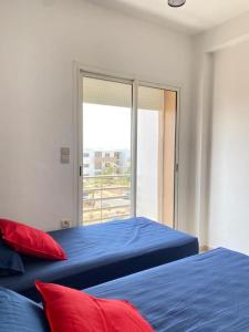 a bedroom with two beds and a sliding glass door at Appartement standing avec piscine à ImiOuaddar in Agadir