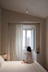 a woman sitting on a bed looking out a window at P10 DESIGN in Rome
