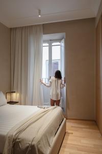 a woman looking out the window of a bedroom at P10 DESIGN in Rome