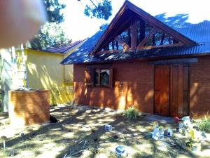 uma casa com uma porta de madeira num quintal em La casa del búho em Mar de Ajó