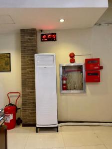 Asiatel Airport Hotel في مانيلا: ثلاجة في غرفة مع ساعة على الحائط