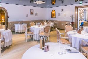 ein Esszimmer mit weißen Tischen und Stühlen in der Unterkunft LOGIS Hôtel & Restaurant Le Soleil D'or in Montigny-la-Resle