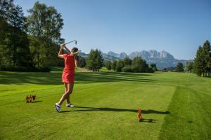 a woman in a red dress playing golf on a field at Ski & Golf Auszeit Apartment by Alpine Host Helpers in Kitzbühel