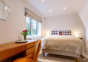 1 dormitorio con cama, escritorio y ventana en Haons, en Biddenden
