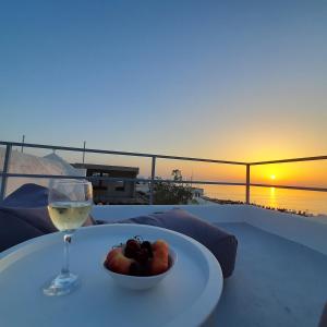 a table with a glass of wine and a bowl of fruit at OUTOPOIA CAVE STUDIOS in Oia