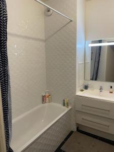 a white bathroom with a tub and a sink at Le jardin de Clémentine & Julien in Saint-Ouen