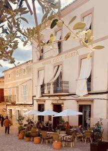 a hotel with tables and umbrellas in front of a building at Casal d'Artà by Baudot 1926 - Adults Only in Artá +24 photos