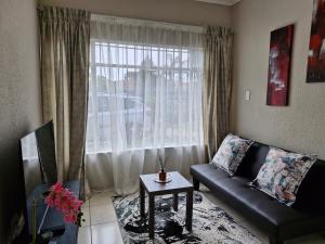 a living room with a couch and a window at Botle Hive in Kempton Park