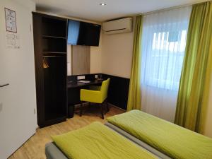Habitación con 2 camas y escritorio con silla amarilla. en Hotel Gästehaus Stock Zimmer Trüffeleckle en Friedrichshafen