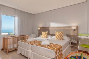 a bedroom with two beds and a large window at Landmar Costa los Gigantes in Puerto de Santiago