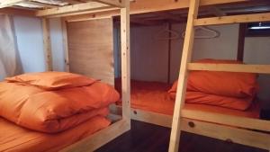 two bunk beds with orange pillows in a room at Guesthouse MI CASA SU CASA in Zentsuji