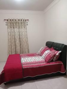 a bed with a red blanket and pillows on it at D GARDEN HOME STAY in Tanah Merah