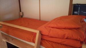 a bed with an orange comforter in a room at Guesthouse MI CASA SU CASA in Zentsuji