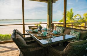 a dining table on a porch with a view of the beach at Villa Blue Hole in Mangrove Cay