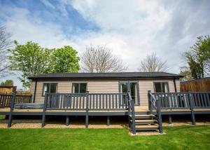 een stacaravan met een groot terras en een huis bij Lee Valley in Hoddesdon