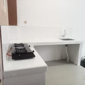 - une cuisine blanche avec cuisinière et évier dans l'établissement Bima guest house, à Ngadipuro