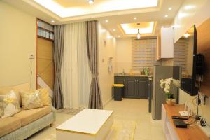 een woonkamer met een bank en een keuken bij Gail Homes Naalya - One bedroom luxury apartment in Kampala
