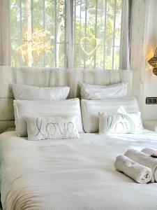 a white bed with white pillows and a window at Casa completa para parejas jacuzzi piscina y wifi cerca al Caminito del Rey Málaga España in Alora