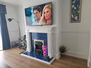 a living room with a fireplace with a tv on the wall at Orpington North Townhouse in Orpington