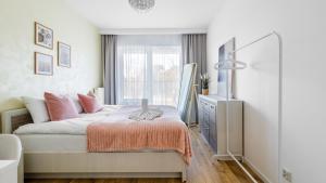 a bedroom with a bed with pink pillows and a television at Comfy Apartments - Morska Bryza in Gdańsk