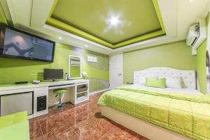 a green bedroom with a bed and a flat screen tv at Jara Changwon in Changwon