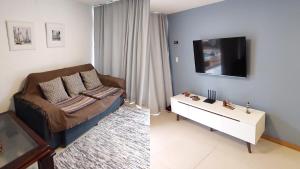a living room with a couch and a tv at Vilage Aconchegante - Imbassaí in Imbassai