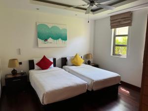 two beds in a room with white walls and colorful pillows at Wonderful villa Harmony BangTao beach in Bang Tao Beach