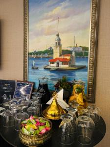 a table with glasses and a painting of a lighthouse at Aprilis Gold Hotel - Special Category in Istanbul