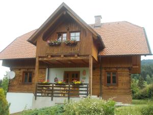 Cette maison en bois dispose d'un balcon fleuri. dans l'établissement Ferienhaus Karin, à Rieding