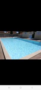 a large swimming pool with blue water at Villa 6p piscine spa privatif wifi proche des plages in Le Barcarès
