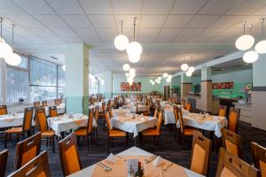 une salle à manger avec des tables, des chaises et des lumières dans l'établissement Hotel Běhounek, à Jáchymov