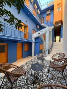 un patio con sillas y mesas frente a un edificio en The blue house Athens, en Atenas
