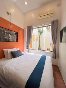 a bedroom with a large bed with an orange wall at Nguyễn Villa Royale in La Gi