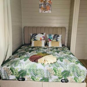 a bed with a blanket on top of it at Palmier bungalow- piscine in Gros-Morne